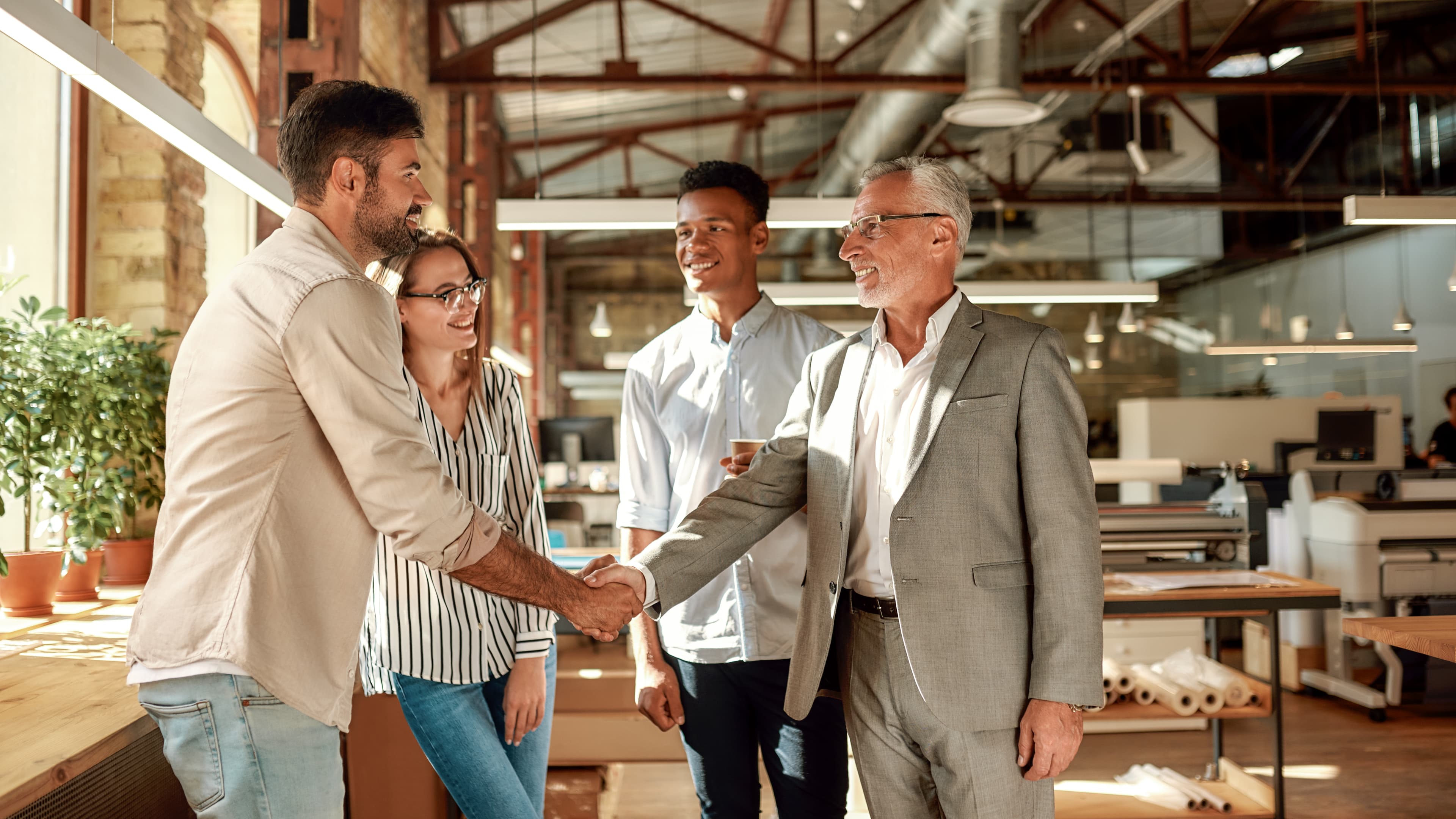 Business colleagues shaking hands and smiling together in a modern office