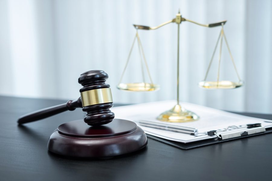A judge's gavel and scales of justice beside a signed legal document on a desk