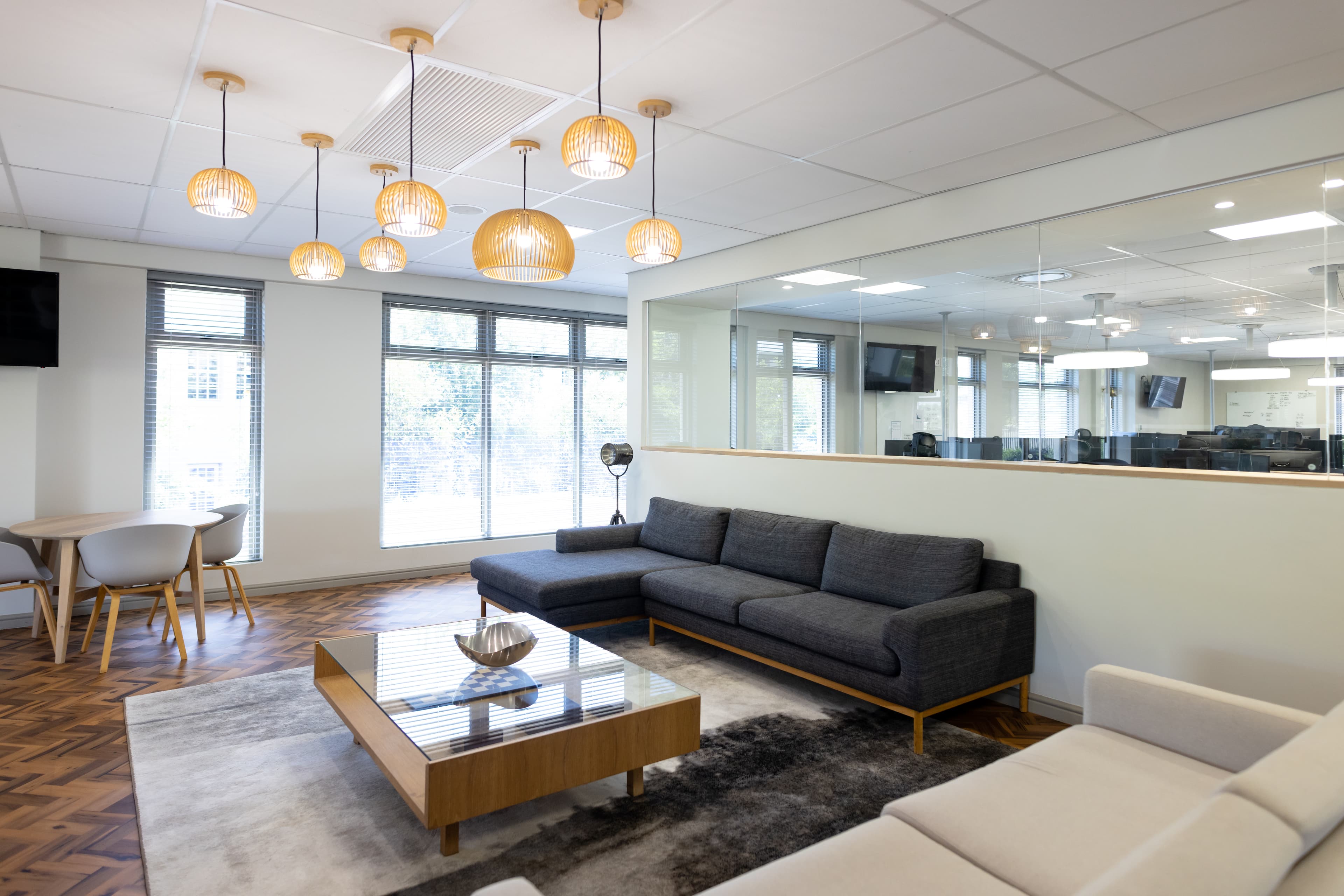 A modern office lounge with a glass wall and lounge seating