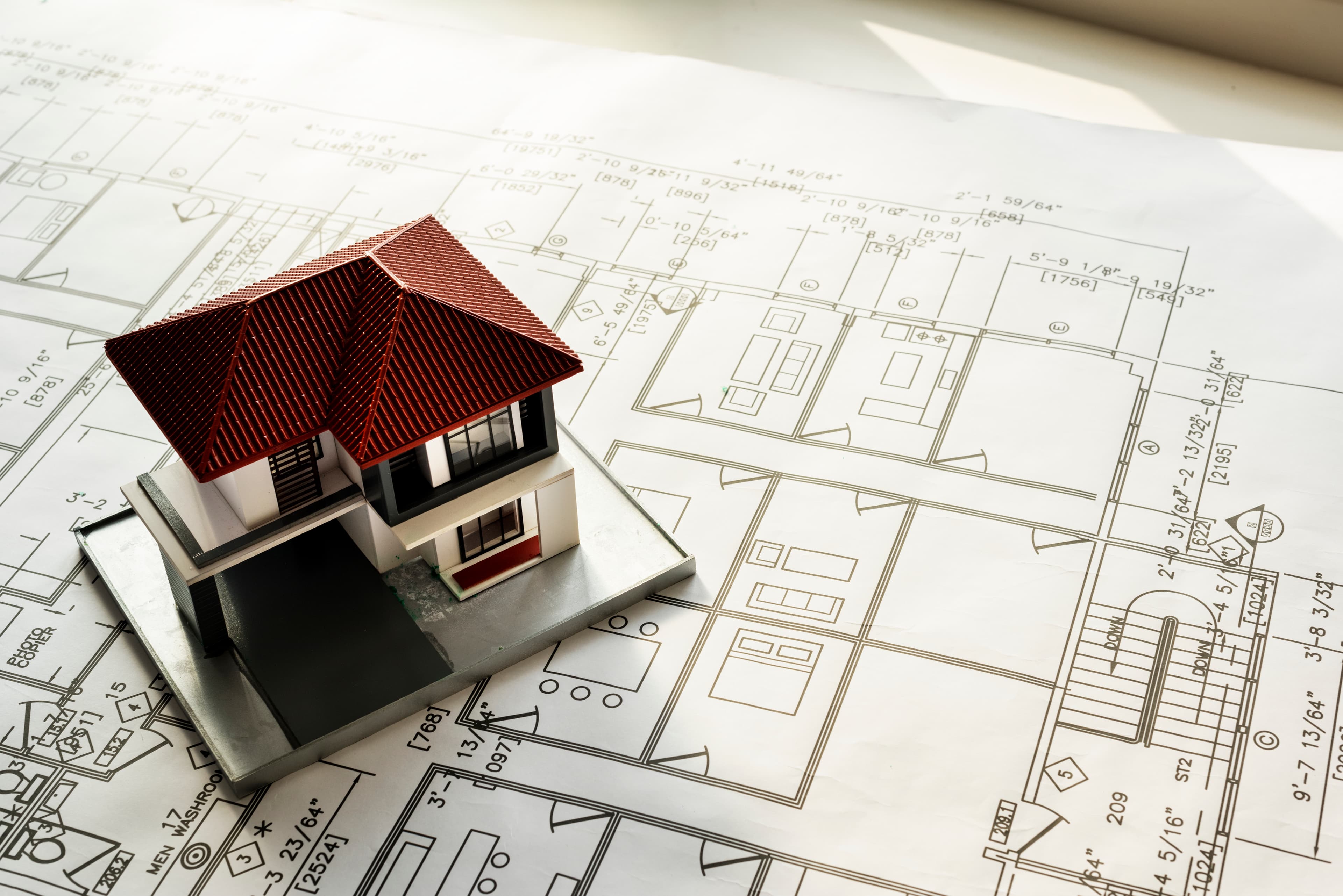 An architectural model house on top of building blueprints